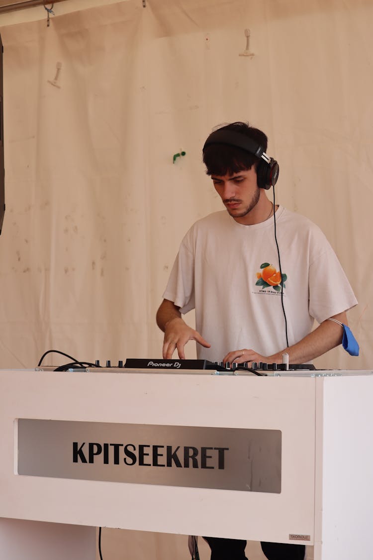 A Man Using DJ Mixer And Headphones 