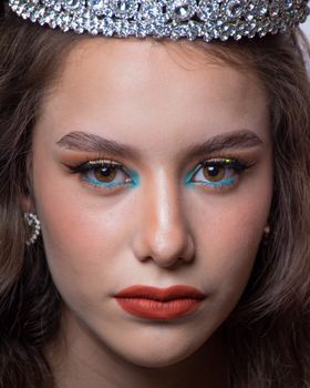 Close-up portrait of a woman with red lips, blue eyeshadow, and a diamond crown in Mexico City.
