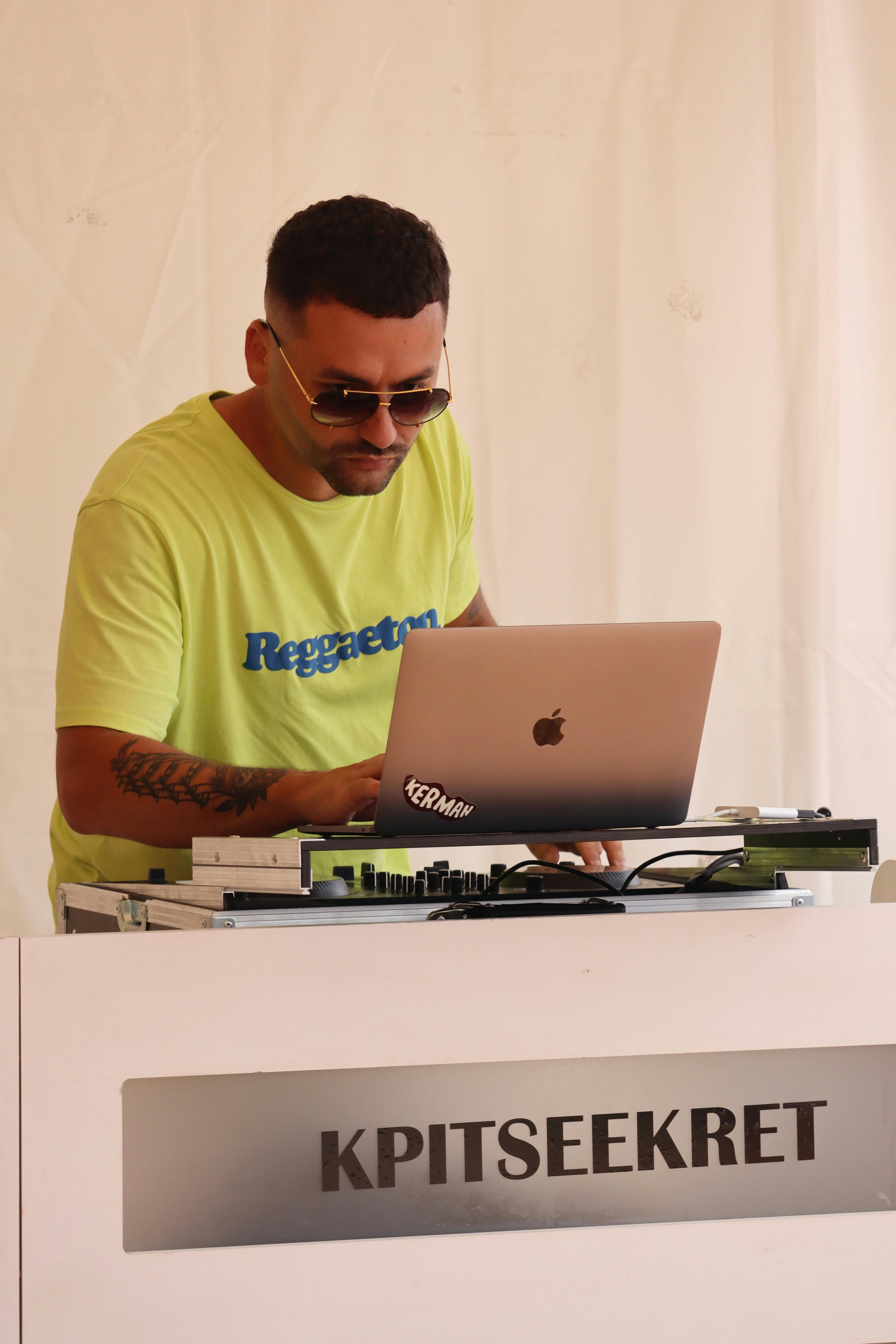 DJ mixing music with laptop and equipment during a live event performance.