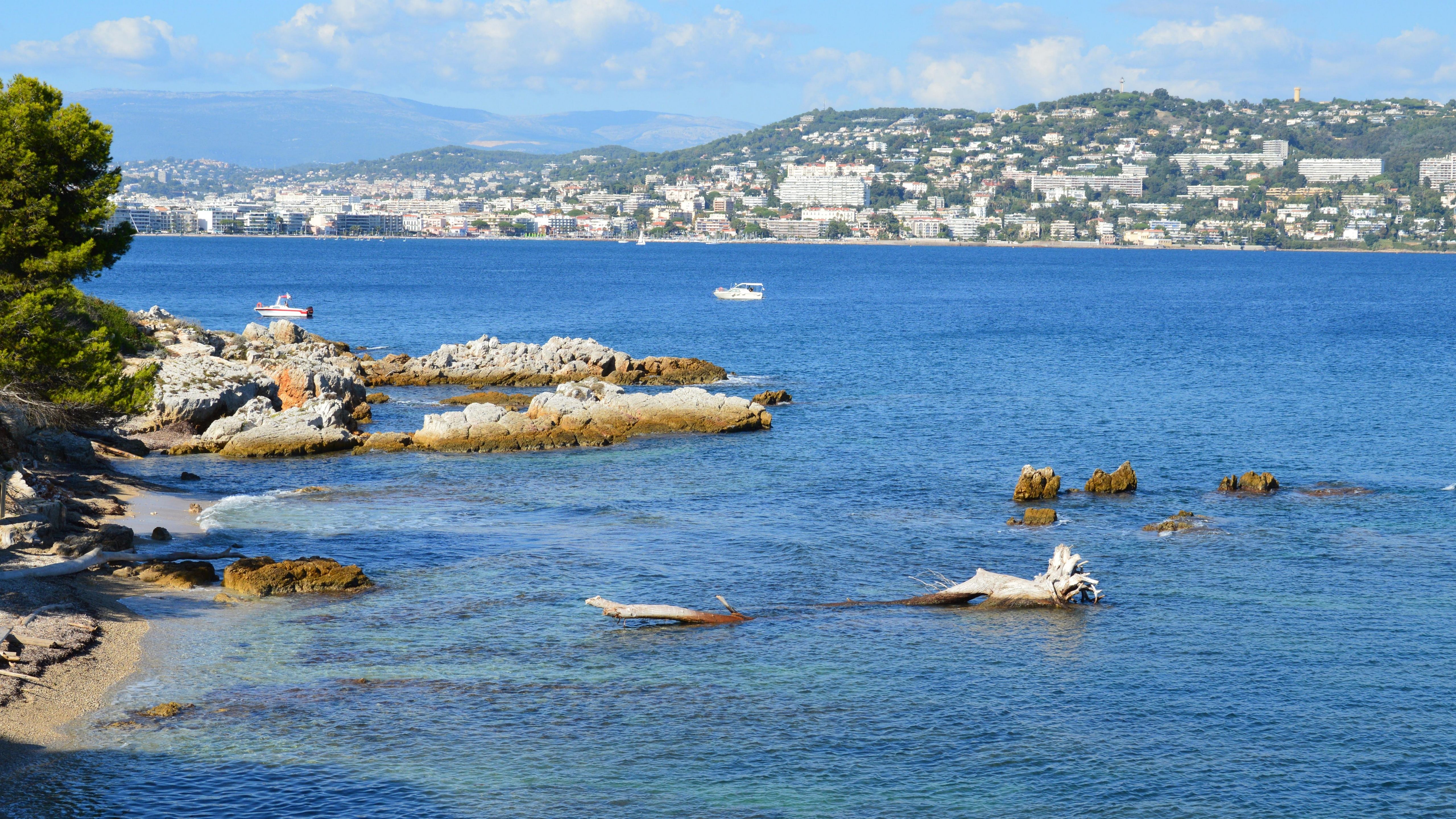 A serene coastal scene with rocks and clear blue sea under a bright sky. A serene coastal scene with rocks and clear blue sea under a bright sky.