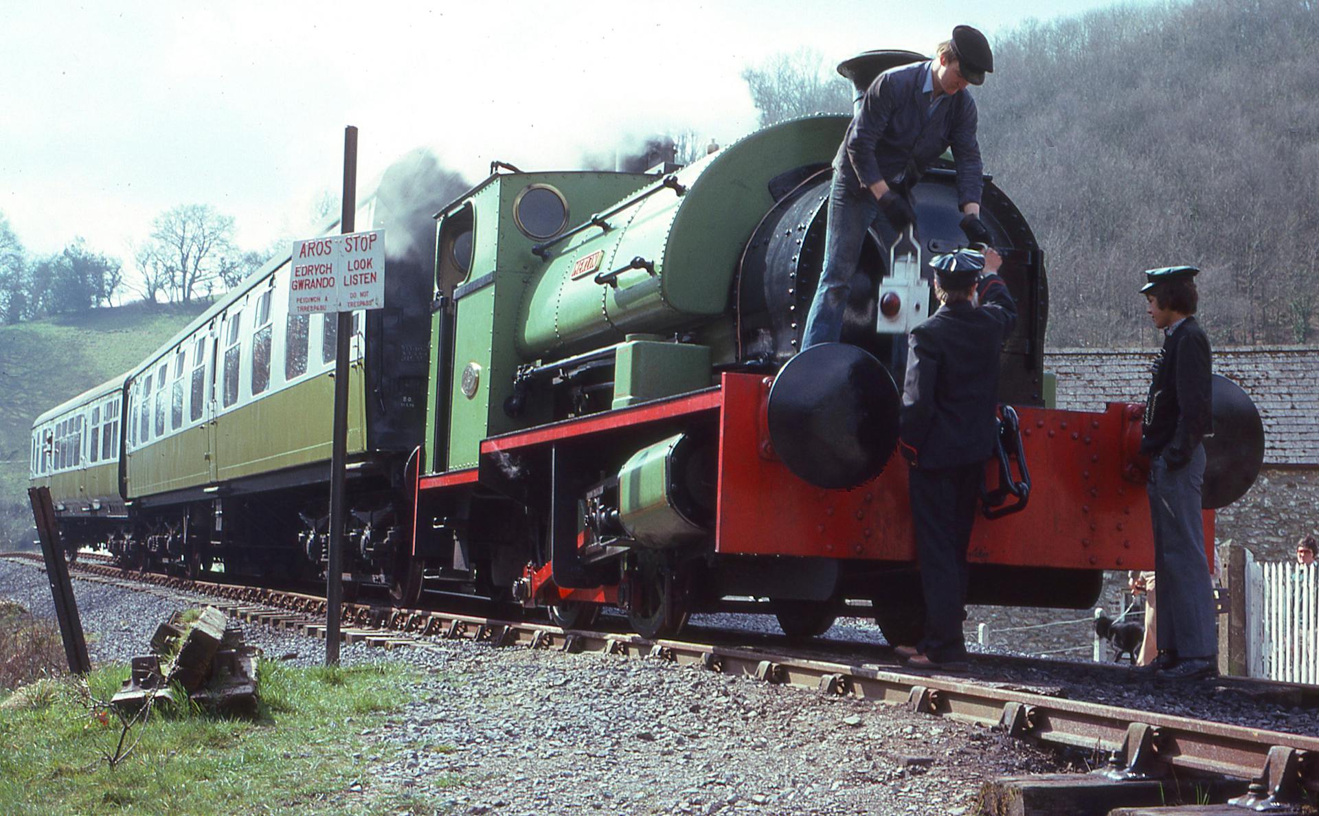 A nostalgic scene featuring a vintage steam train being inspected by railway workers.