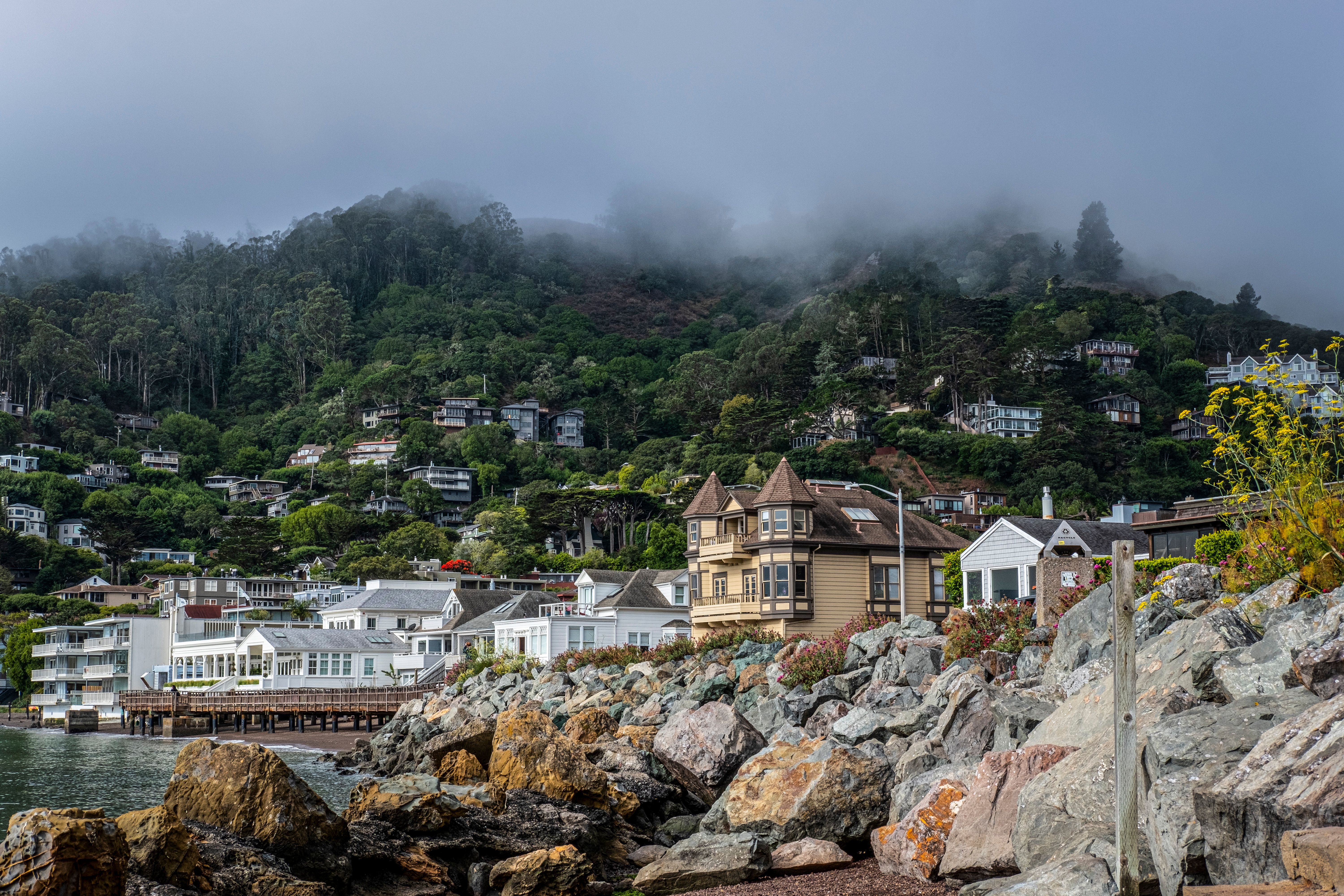 A picturesque seaside town with charming houses, rocky shore, and mist-covered hills. A picturesque seaside town with charming houses, rocky shore, and mist-covered hills.