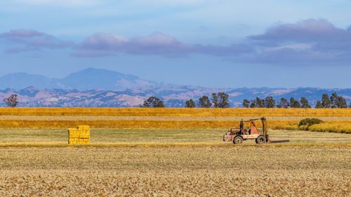 Free Rustic tractor in a vast rural landscape with mountains in the distance on a clear day. Stock Photo
