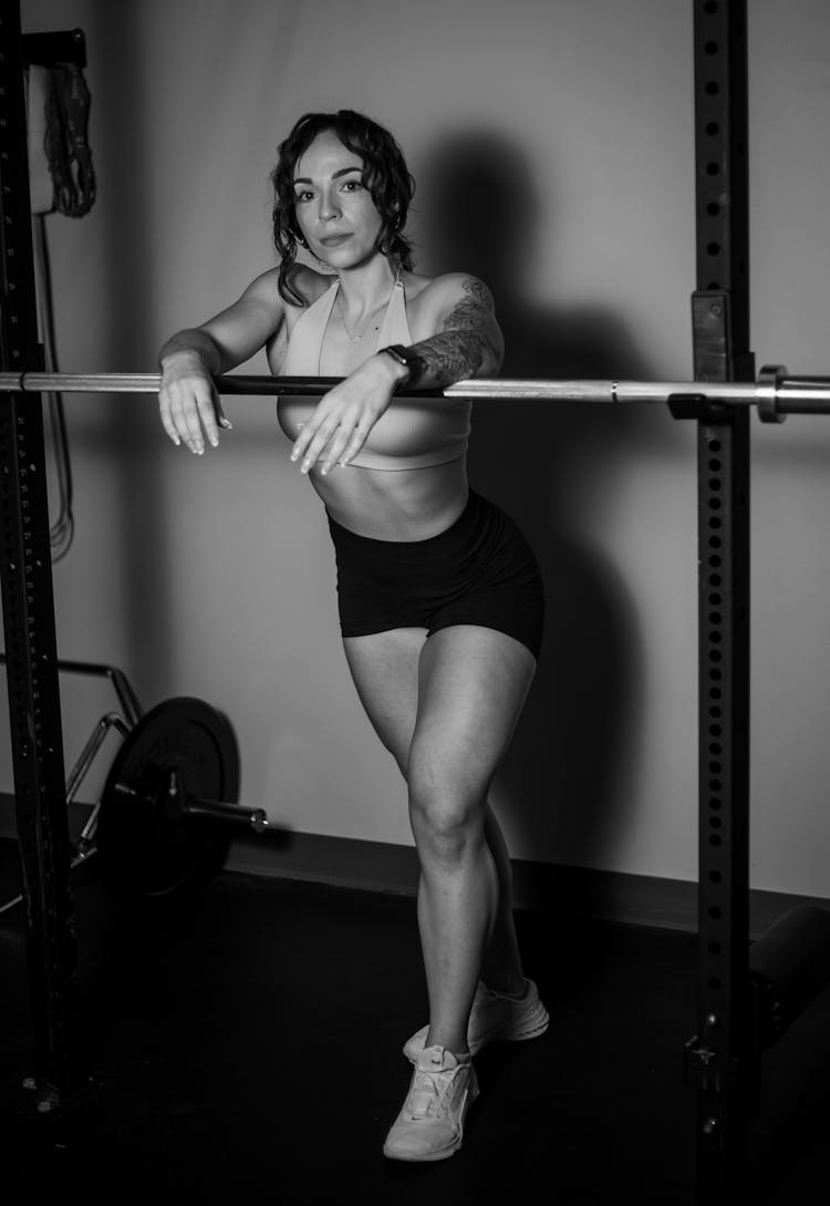 Black And White Photo Of Woman In Sports Bra And Shorts Posing On Gym 