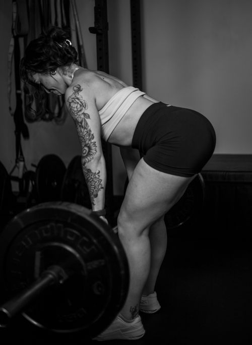 Free A tattooed woman performing deadlifts with a barbell in a gym, emphasizing strength and fitness. Stock Photo