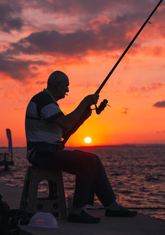 Silhouette of a Man Fishing During Sunset · Free Stock Photo