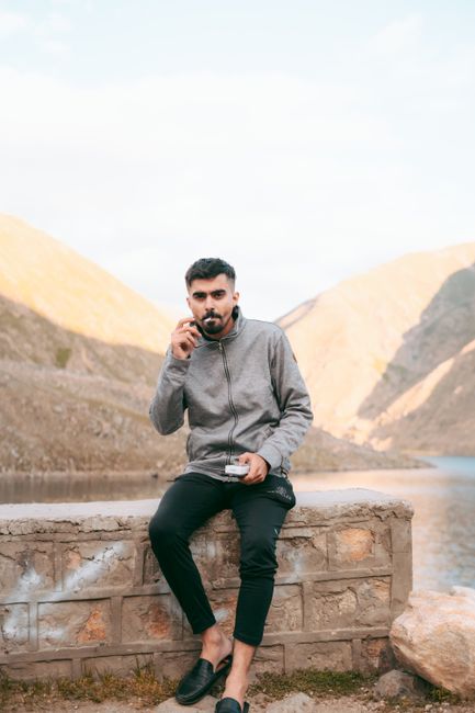 Man enjoying a smoke while sitting on a bench against a mountainous backdrop. - Where to Buy Quality Shilajit in Pakistan