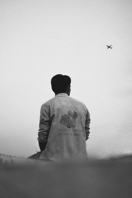 Back view of man watching an airplane in a black and white setting.