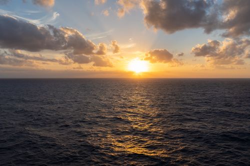 Free Breathtaking view of the ocean during sunset with golden light reflecting off the water. Stock Photo