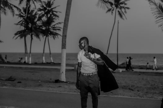 A black and white portrait of a man standing by the beach in Abidjan, Côte d'Ivoire.