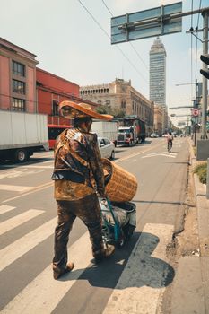A man in a sombrero crosses a busy street in Mexico City, highlighting urban life.