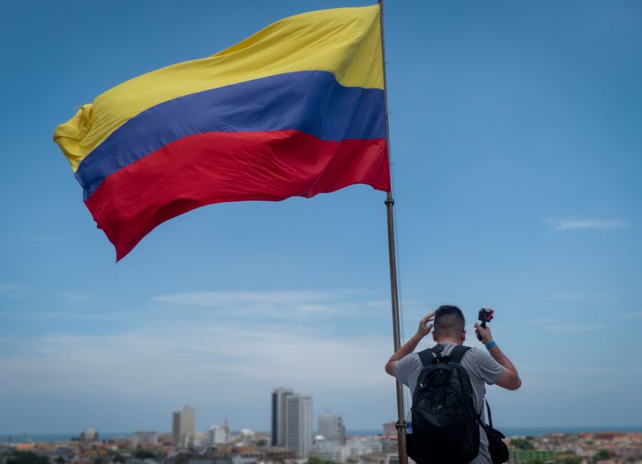 Back view of a man photographing the Colombian flag in Cartagena, Colombia.