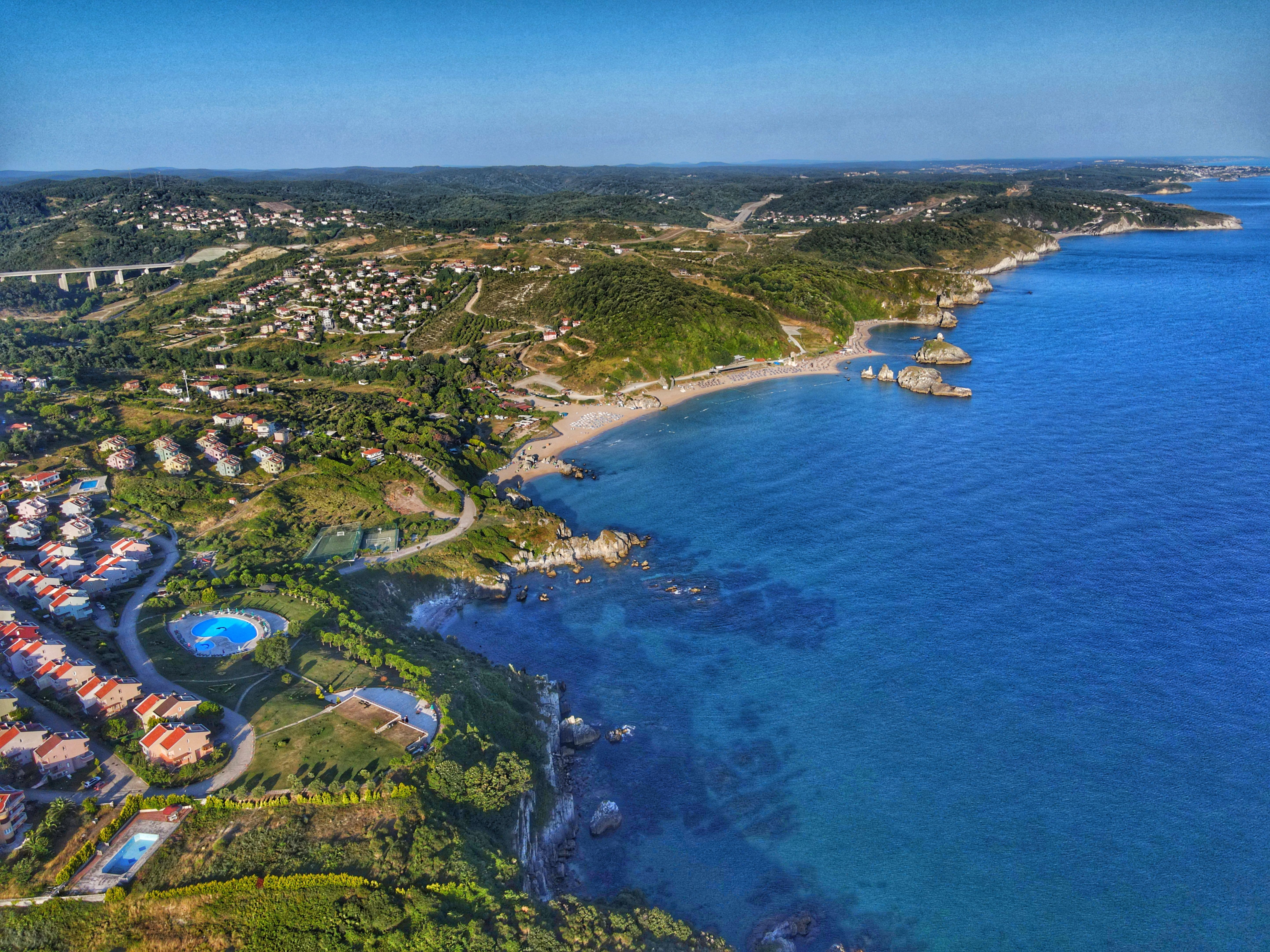 A stunning aerial view of a coastal town near İstanbul with clear blue waters and green hills.
