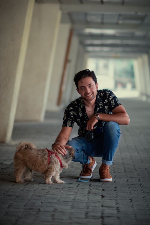 Free Man crouching with a small dog under an urban walkway, showing companionship. Stock Photo