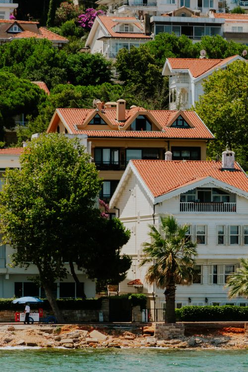 Free Charming coastal houses with lush greenery and scenic shoreline view. Stock Photo