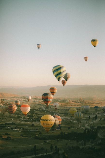A serene view of colorful hot air balloons floating over Cappadocia, Turkey at sunrise.