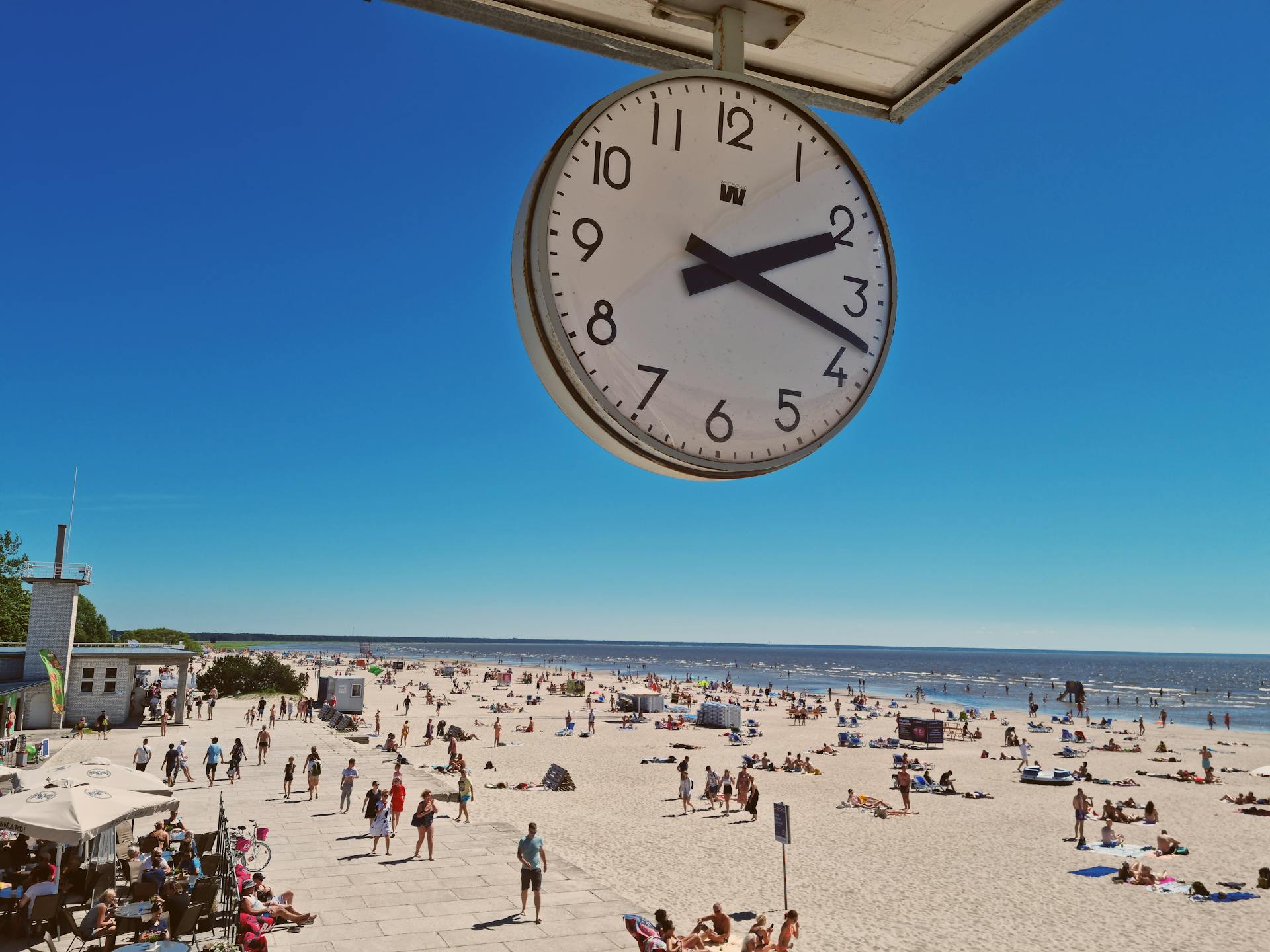 A lively summer day at Pärnu Beach captured under a clear blue sky with a prominent clock view.