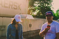 一对戴着帽子的夫妇在纽约市享受着温暖的一天，喝着饮料，十分放松