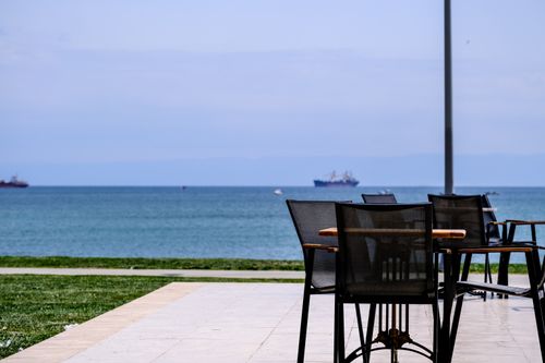 Free Tranquil outdoor cafe setting in İstanbul with a view of the sea and ships. Ideal for summer relaxation. Stock Photo