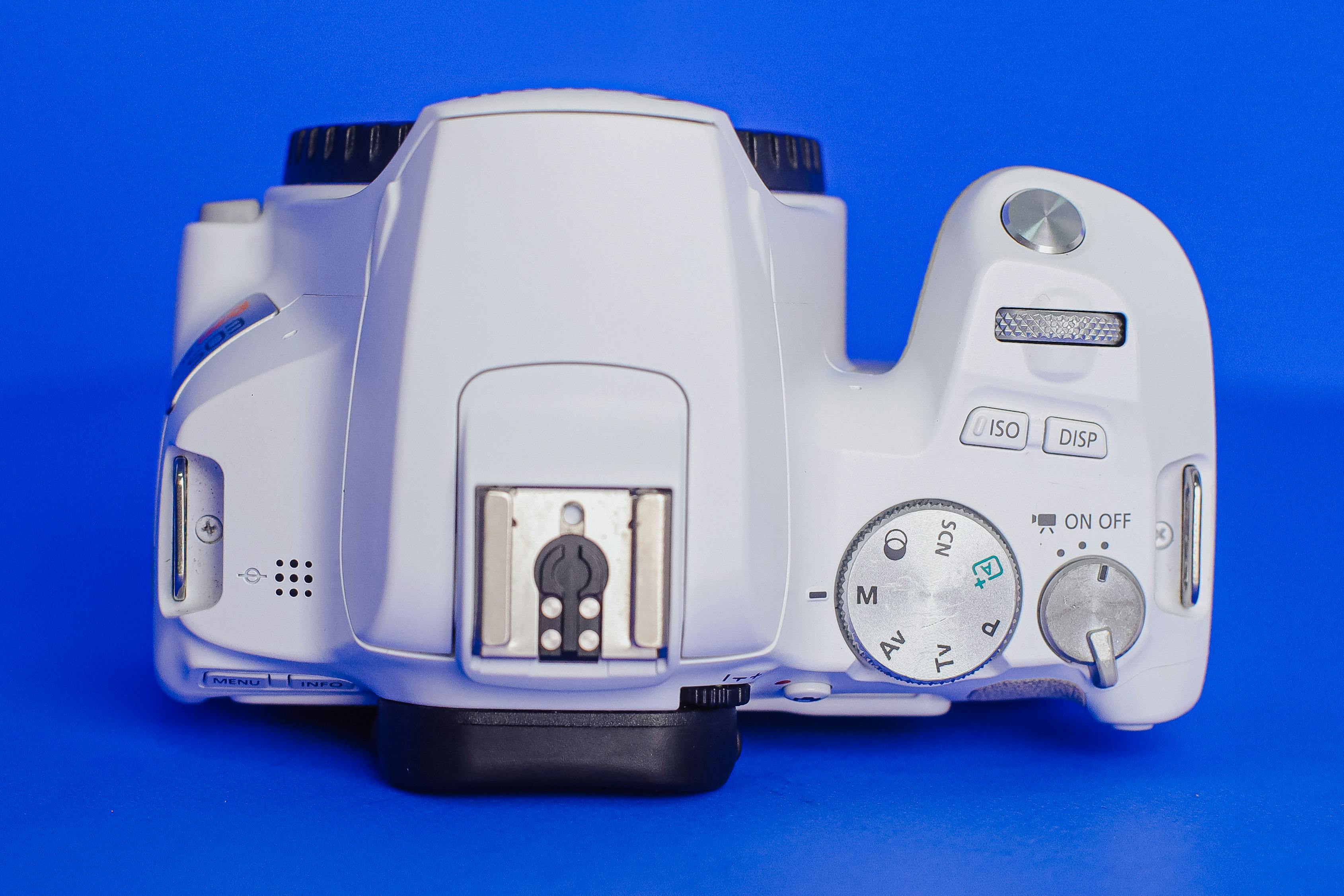 Free Close-up view of a white camera on a blue surface highlighting controls. Stock Photo