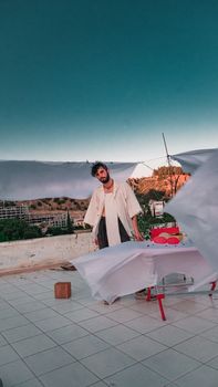 Young stylish man posing on a rooftop with a scenic landscape and vibrant colors.