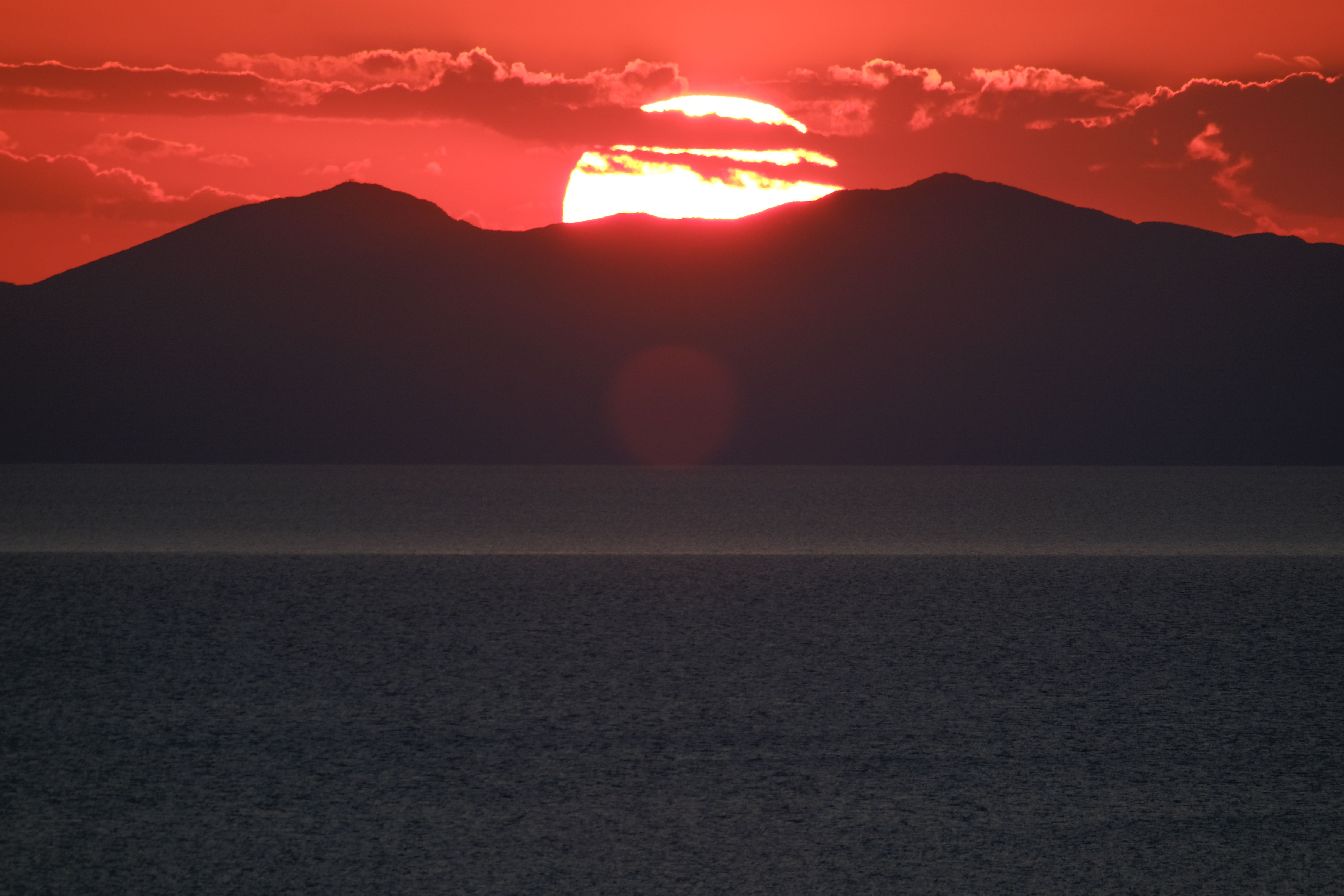 Silhouette of a Mountain near Ocean during Sunset · Free Stock Photo