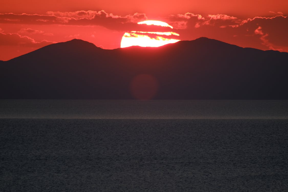 Silhouette of a Mountain near Ocean during Sunset