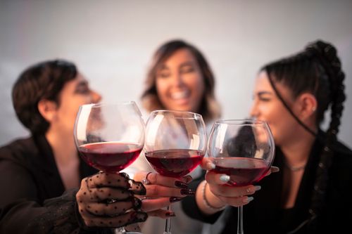 Free Three friends cheerfully toasting with red wine, celebrating a special moment together. Stock Photo