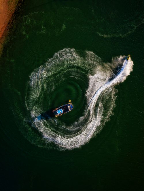 Free Dynamic aerial photo capturing a jetski circling near a boat in Devon's vivid waters. Stock Photo