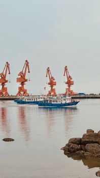 Vibrant industrial port with cranes and boats in Tianjin, China.