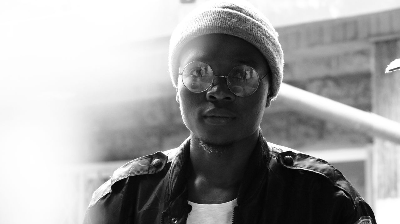 black and white portrait of a young man wearing glasses and a beanie o
