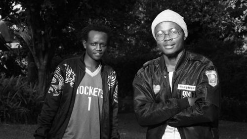 Free Black and white photo of two young men in stylish outfits outdoors, showing camaraderie. Stock Photo