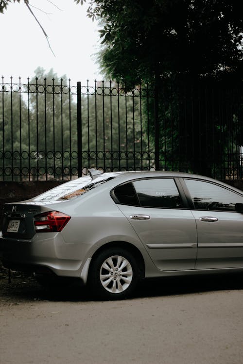 Silver Sedan Parked Near Black Metal Fence