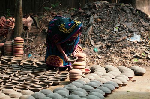 Free A woman arranges handmade clay pots outdoors in Dhaka, Bangladesh. Stock Photo