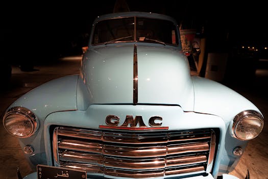Close-up of a vintage blue GMC truck from the front, showcasing its classic chrome details and emblem.