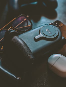 A stylish arrangement of electronic accessories, including a phone, glasses, and earphones on a surface.