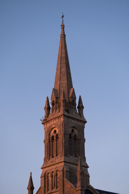 Free Capture of a majestic Gothic church tower against a clear evening sky highlighting its architectural beauty. Stock Photo