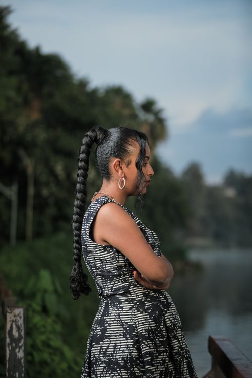 Free A woman in a black patterned dress stands by a serene lake in Oromia, Ethiopia. Stock Photo