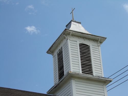 Free Low angle view of a classic white church steeple with cross, set against a clear sky. Stock Photo