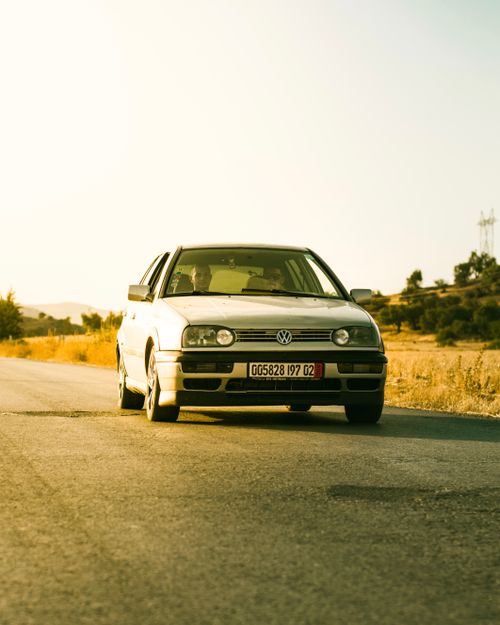 Free A vintage Volkswagen car driving on a sunlit road in Chlef, Algeria, showcasing retro automotive design. Stock Photo