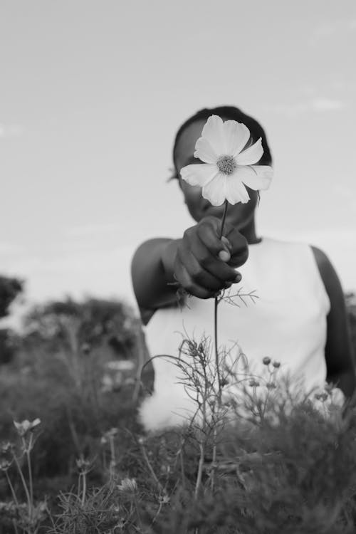 Grayscale Photo of a Person Holding a Blooming Flower