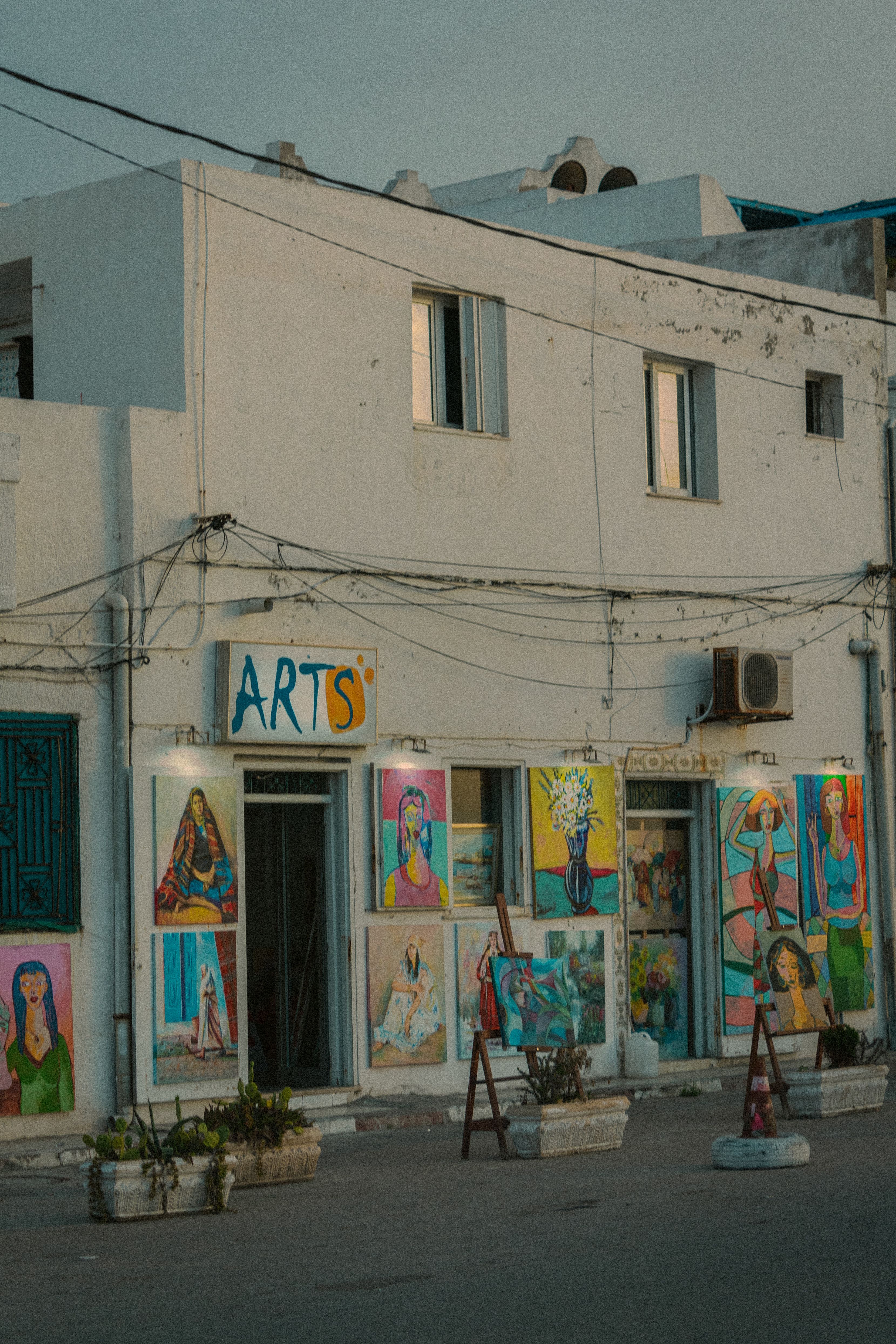 Colorful paintings adorn the facade of an art gallery in a small town.
