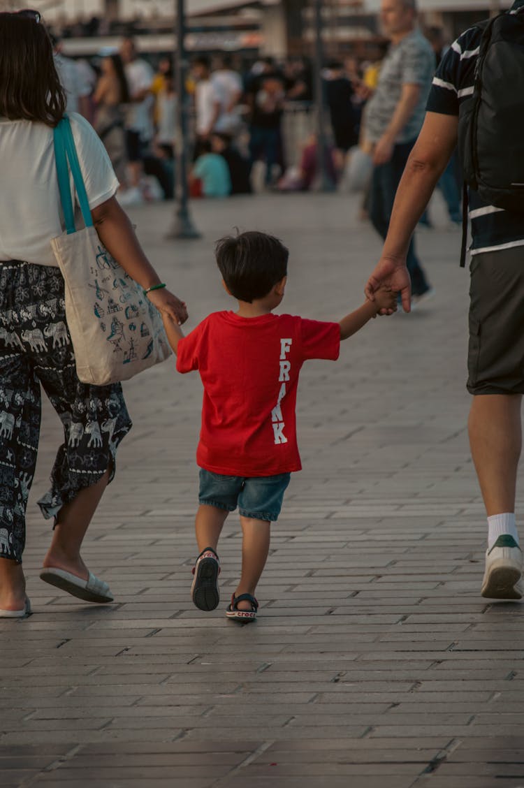 Photo Of A Kid Holding Hands With His Parents