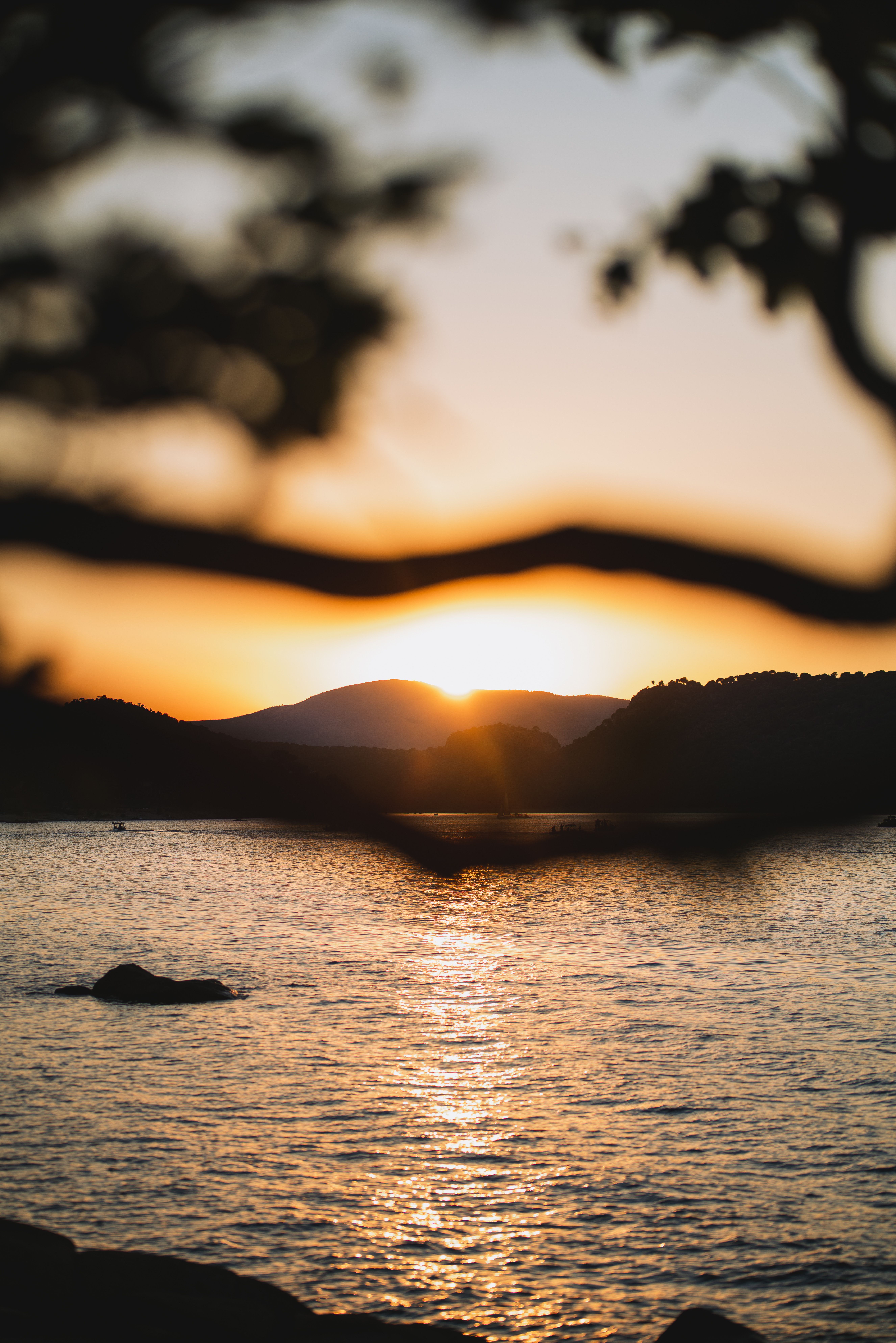 Peaceful sunset scene over a calm lake with mountain silhouettes in the background.