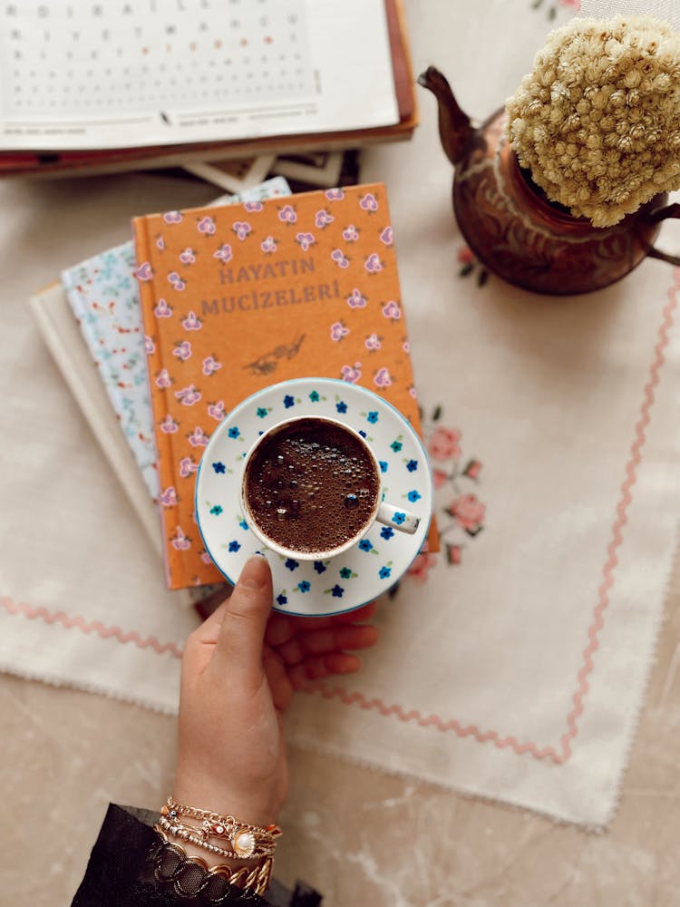 Hand Holding Coffee Cup On A Pile Of Books