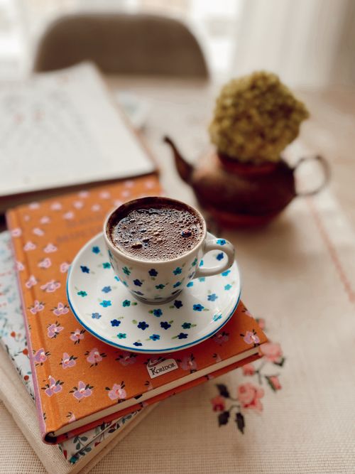 Free A charming scene with a cup of coffee on floral notebooks, perfect for a cozy, creative space. Stock Photo