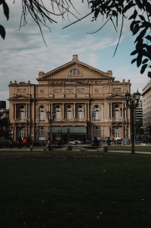 Free Evening view of the iconic Teatro Colón, Buenos Aires showing detailed architecture and lush surroundings. Stock Photo