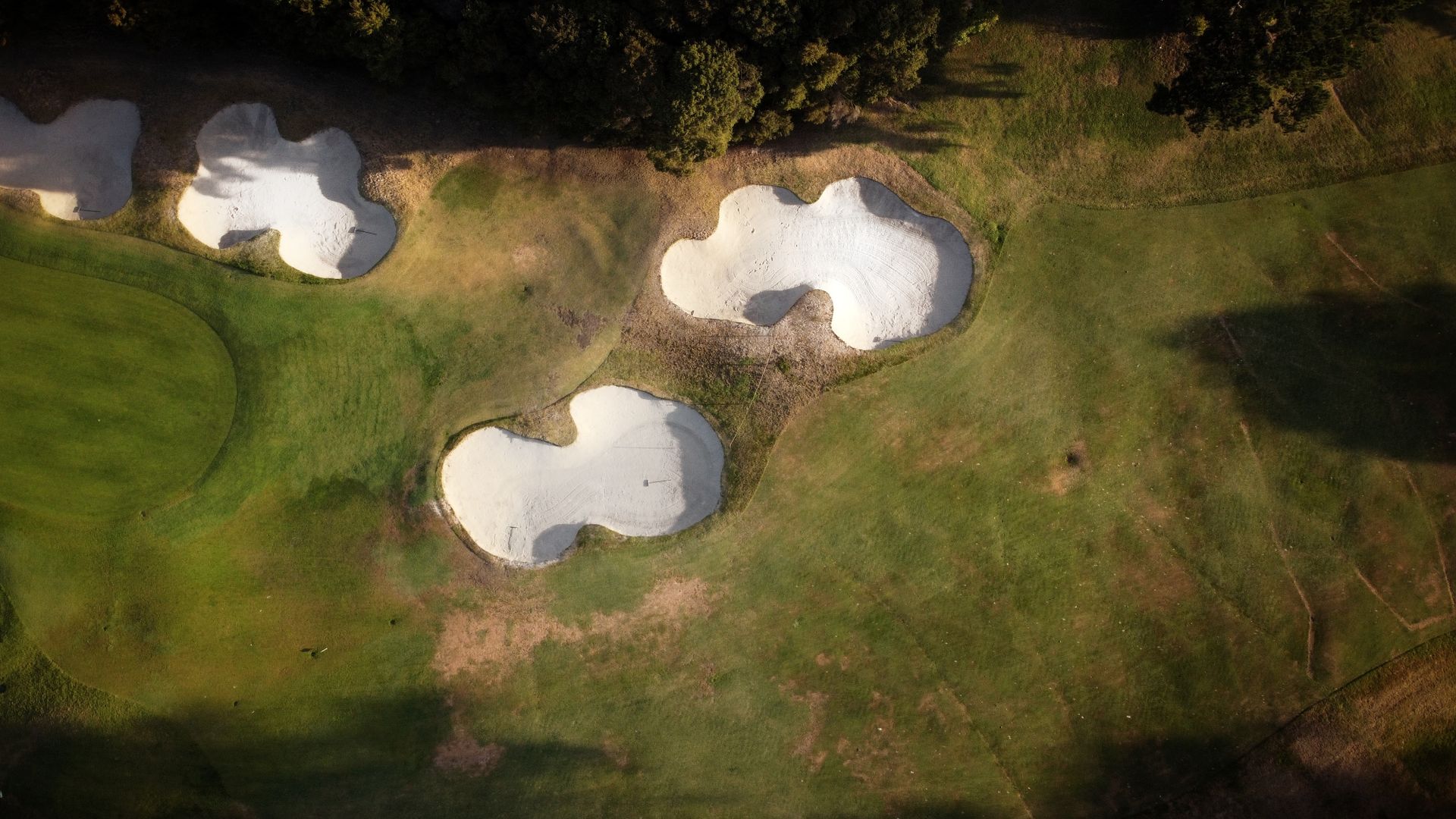 A stunning aerial shot capturing sand traps and green fields on a golf course during daytime.
