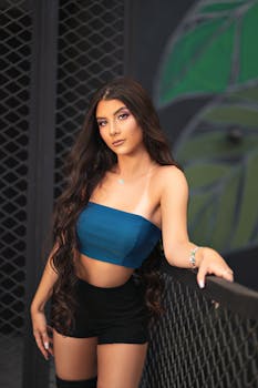 Portrait of a beautiful young woman in a fashionable outfit with long flowing hair, leaning on a railing.