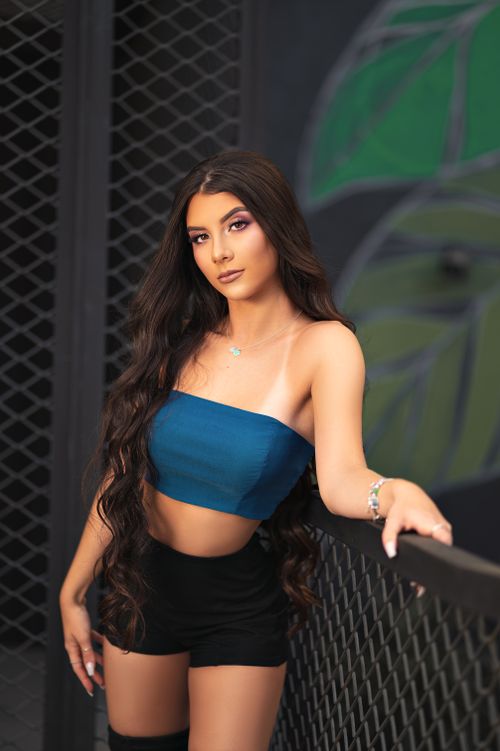 Free Portrait of a beautiful young woman in a fashionable outfit with long flowing hair, leaning on a railing. Stock Photo